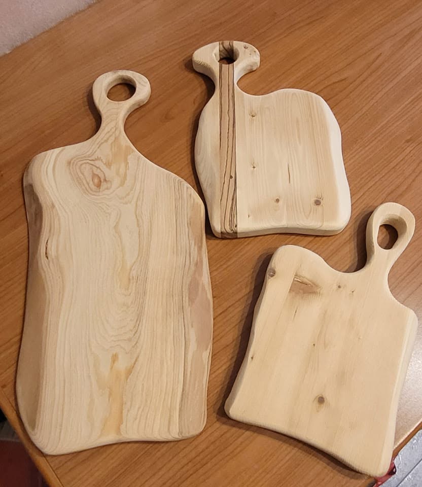 Tre taglieri rustici artigianali in legno massello esposti sul tavolo